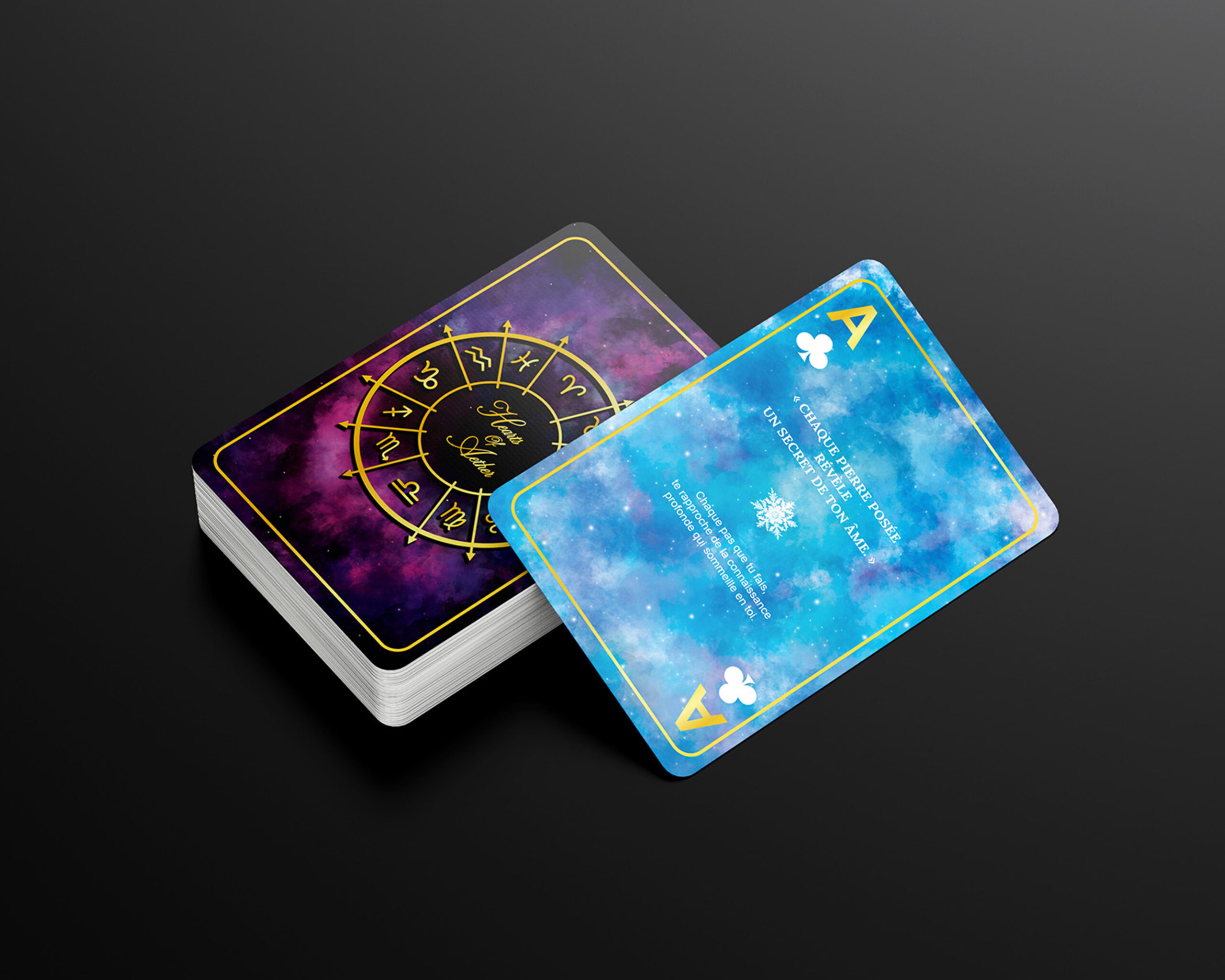 Jeu de cartes astrologiques présenté en pile avec cartes aux univers cosmiques bleus (ton glacial) et violets, intégrant motifs zodiacaux et détails dorés.